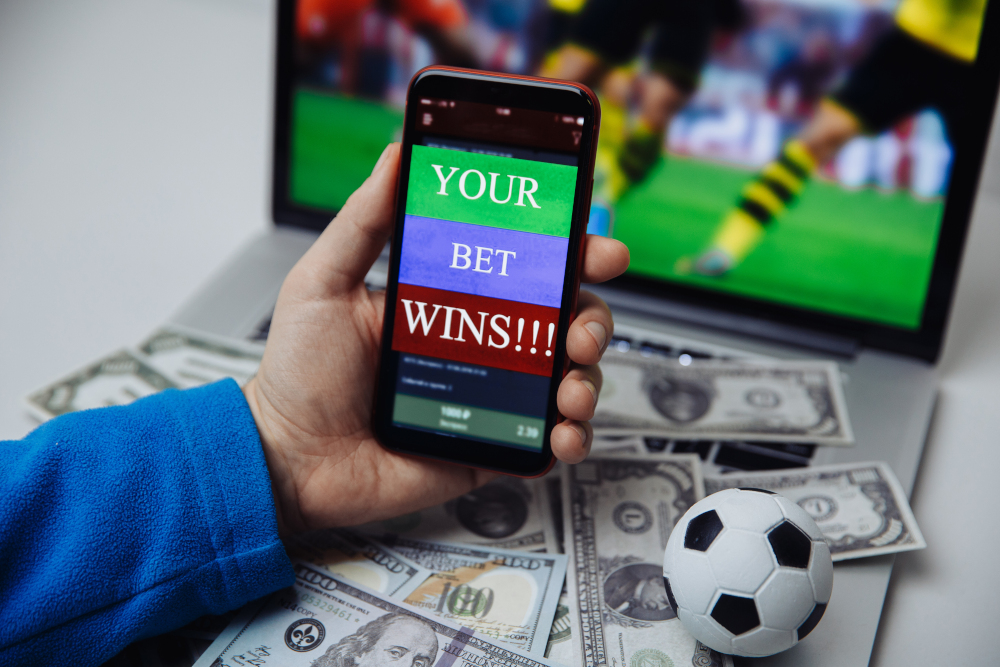 Lucky winner at football betting with phone in hand and dollar bills