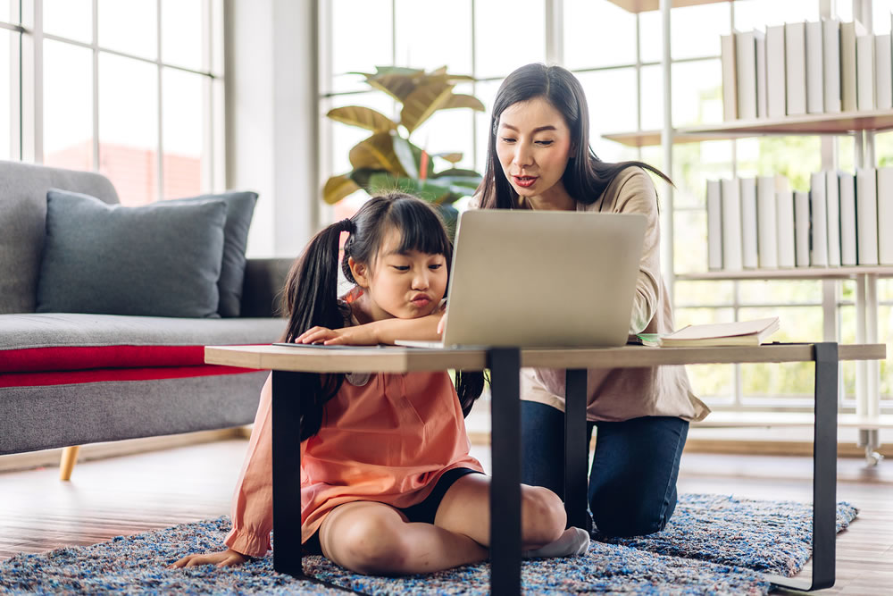 Mother and asian kid little girl learning and looking at laptop computer making homework studying with online education e-learning system