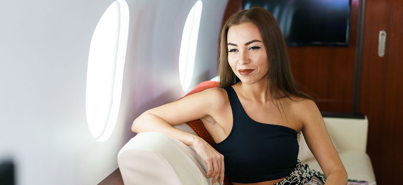 Portrait of caucasian business woman passenger on an airplane, aboard private jet. Young girl travels by plane. Travel concept