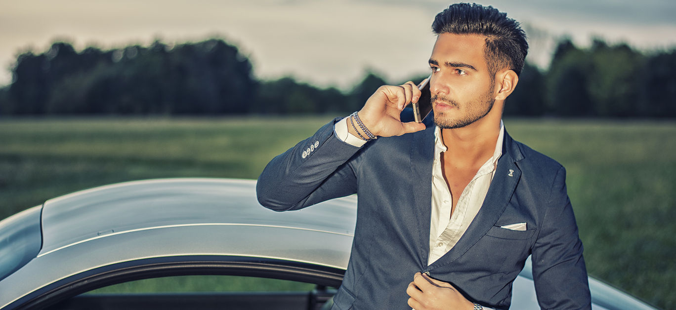 Portrait of young attractiave man in business suit sitting in his new stylish car outdoor in countryside