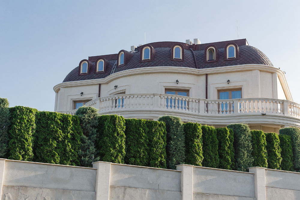 Keeps privacy and security concept. Big luxury house behind the green fence in Byala, Bulgaria.