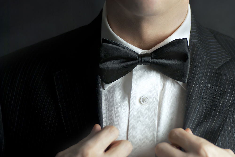 A close-up shot of a man straightening his tux.