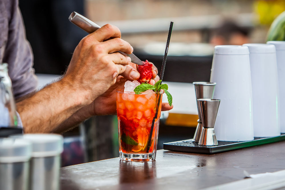 bartender preparing mint and strawberries mojito cocktail on bar