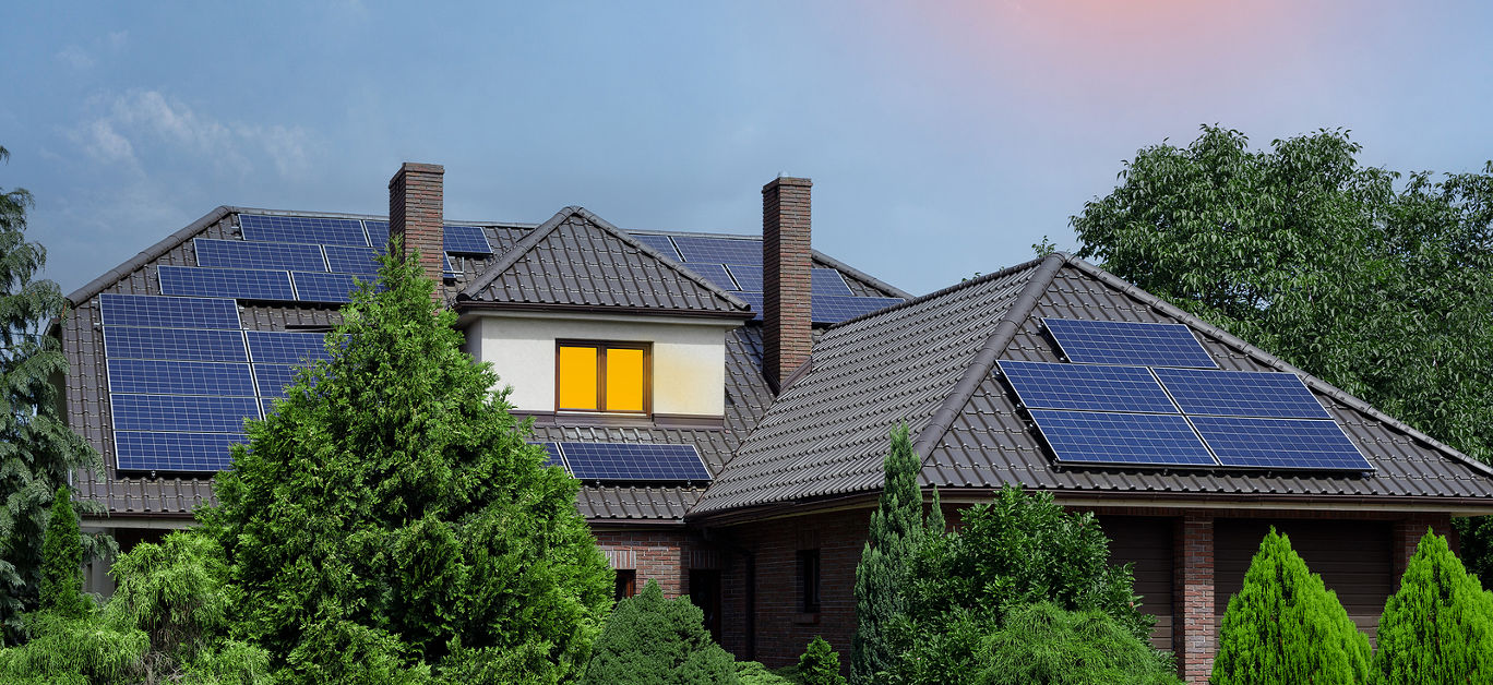 Roof covered with solar panels, large storied house. Sunny weather, Lots of greenery