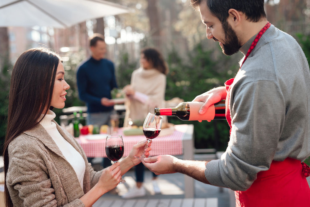 A man and a woman are drinking wine during a picnic with friends