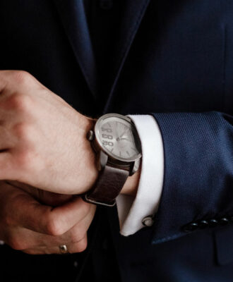 businessman checking time on his wrist watch, man putting clock on hand, groom getting ready in the morning before wedding ceremony. man puts on a watch. selective focus
