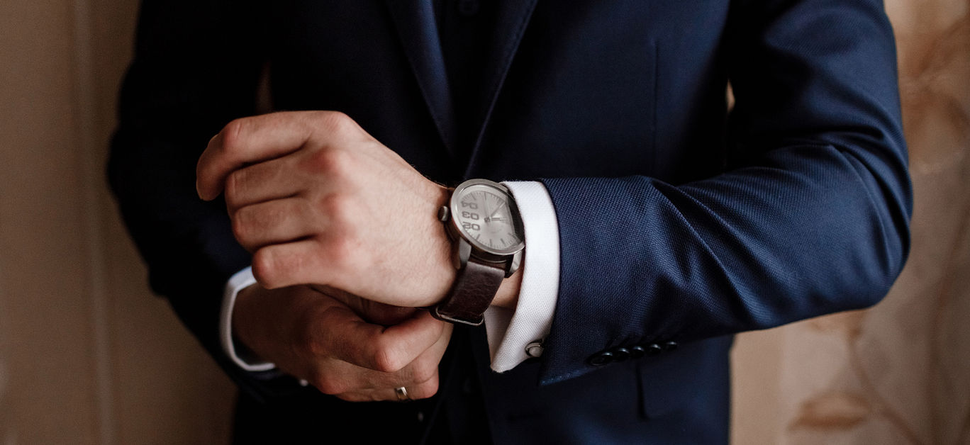 businessman checking time on his wrist watch, man putting clock on hand, groom getting ready in the morning before wedding ceremony. man puts on a watch. selective focus