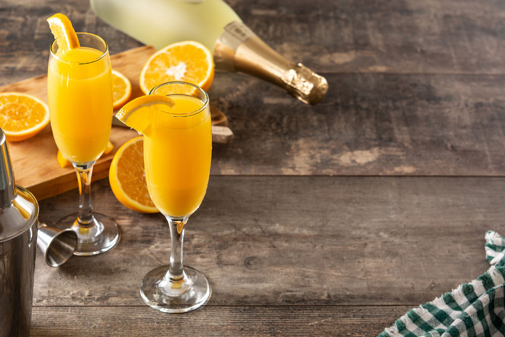 Orange mimosa cocktail on wooden table. Copy space