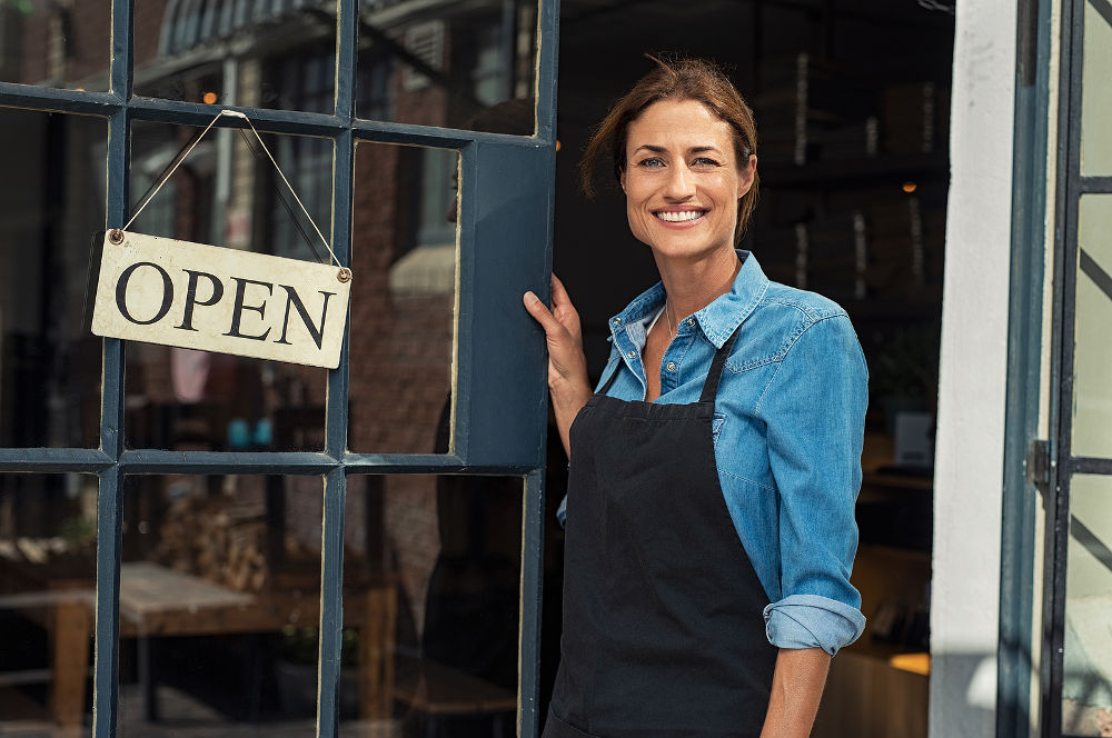 Portrait of a happy waitress standing at restaurant entrance