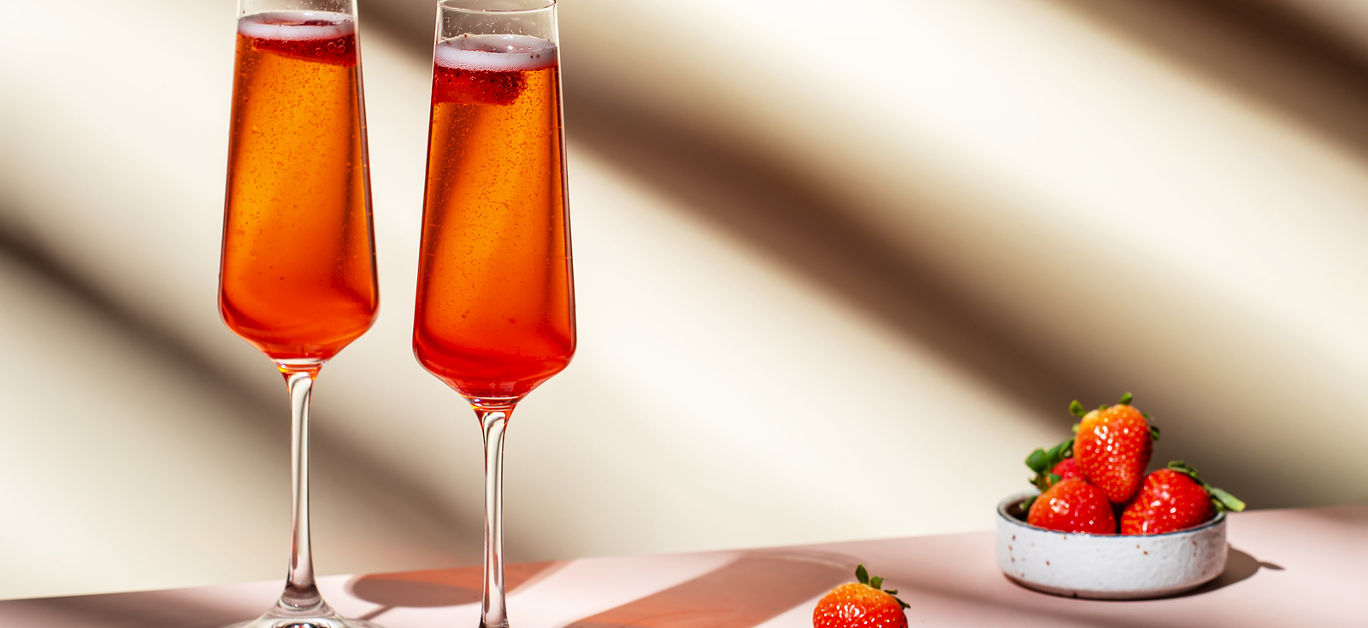 Rossini summer alcoholic cocktail drink with sparkling wine or prosecco, strawberry puree and ice in champagne glasses