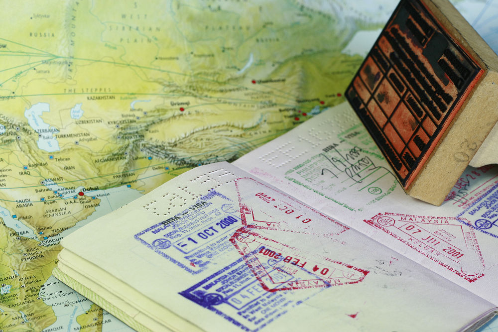 visa stamps on a passport indicting travel with map background