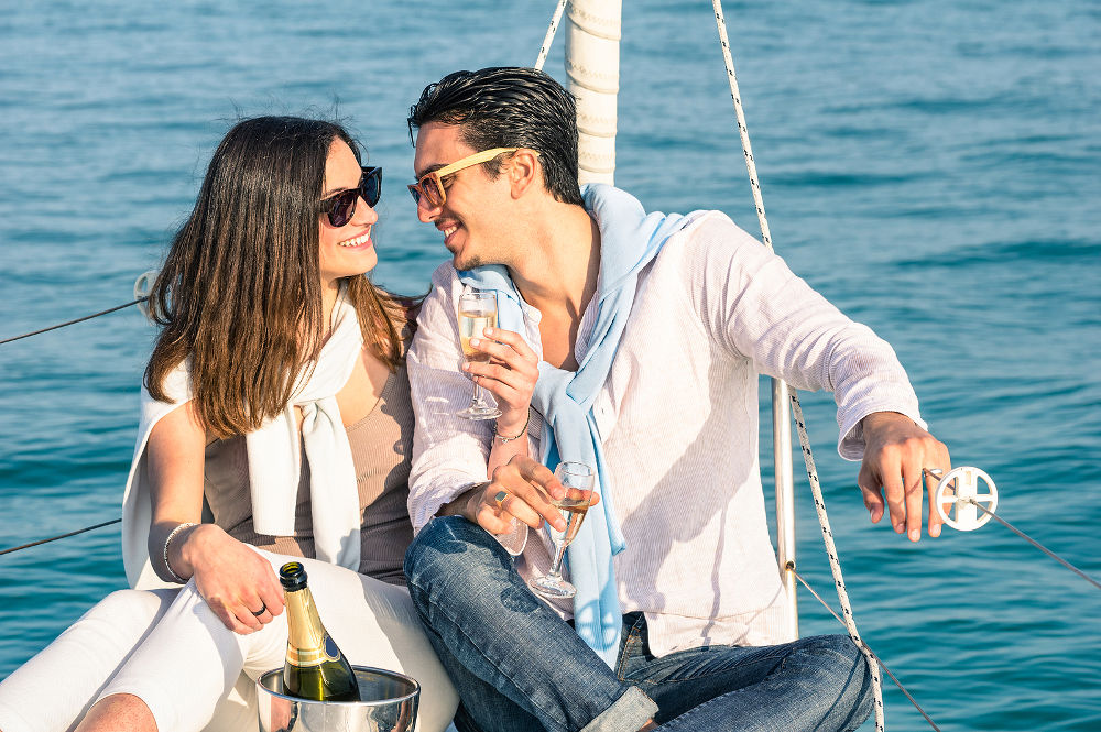 Young couple in love on sail boat with champagne flute glasses