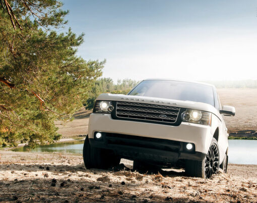 Car Land Rover Range Rover stand on sand near lake and forest at daytime