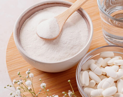 Collagen powder, pills and glass of water on wooden tray, top view