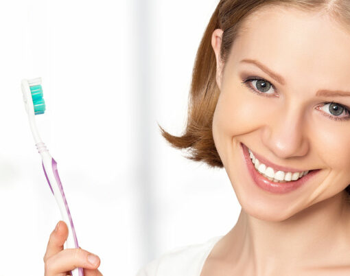 Healthy happy young woman with snow-white smile brushing her teeth with a toothbrush