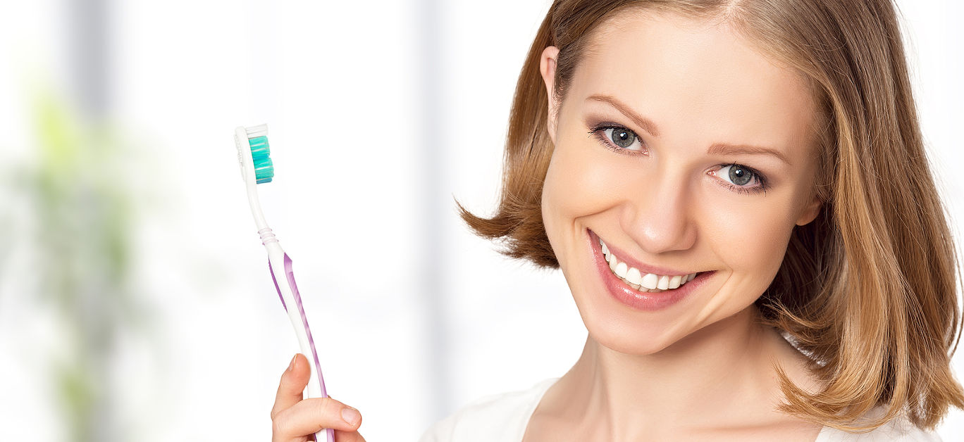 Healthy happy young woman with snow-white smile brushing her teeth with a toothbrush