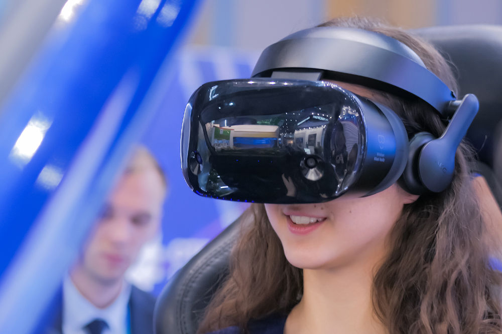 Virtual Reality Exhibition. Woman using virtual reality headset and looking around at technology exhibition