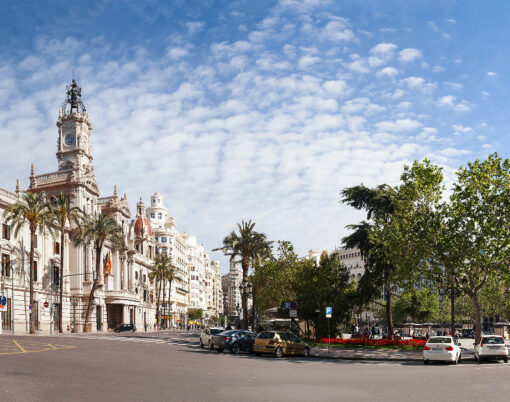 Town square (Plaza del Ayuntamiento) with palm trees and parked cars on a sunny day in Valencia, Spain