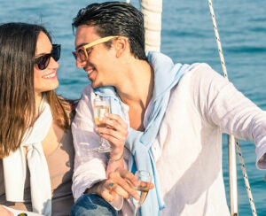 Young couple in love on sail boat with champagne flute glasses