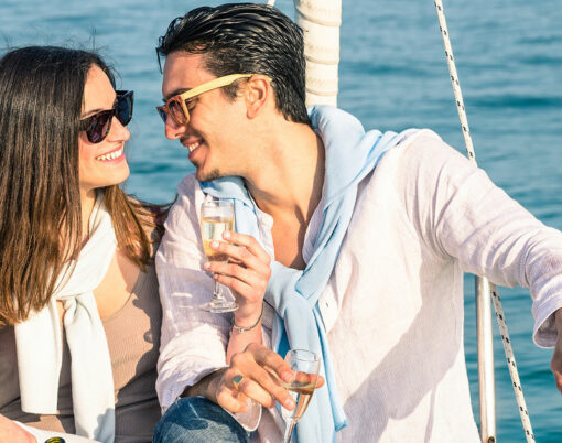 Young couple in love on sail boat with champagne flute glasses
