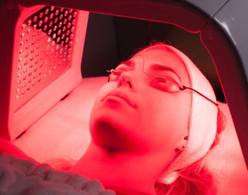 Young woman having LED light facial treatment in beauty salon