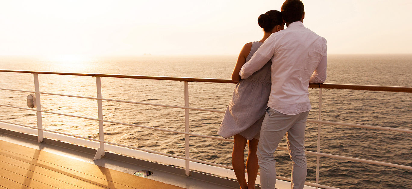 back view of young couple hugging at sunset on cruise ship