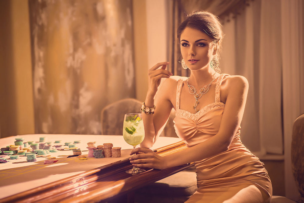 Beautiful young model drinking cocktail in casino