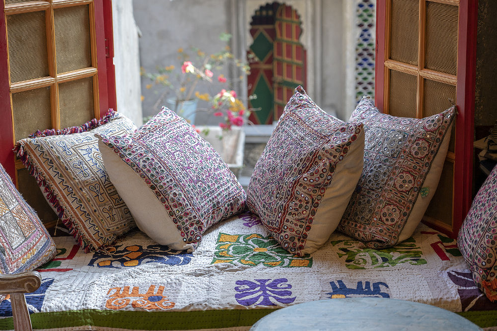 A cozy seating area near the window with colorful pillows with a wonderful view of the courtyard in Udaipur, Rajasthan, India.