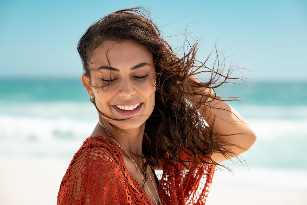 Latin fashion woman wearing red lace dress at beach and enjoy fresh breeze