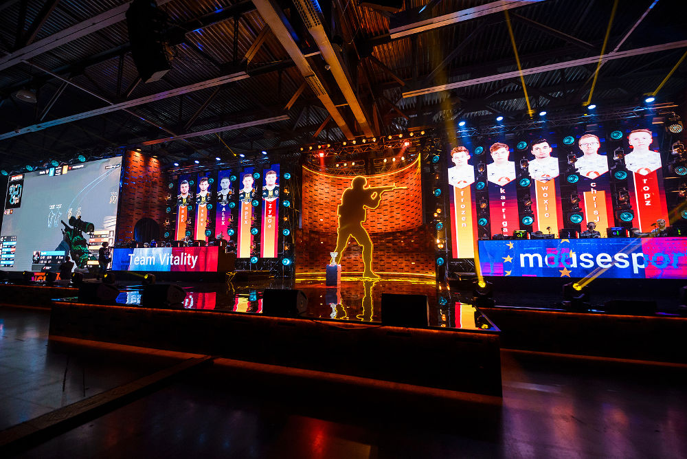 esports Counter-Strike: Global Offensive event. Big illuminated main stage of a computer games tournament located on a big arena. Gamers playing on a stage.