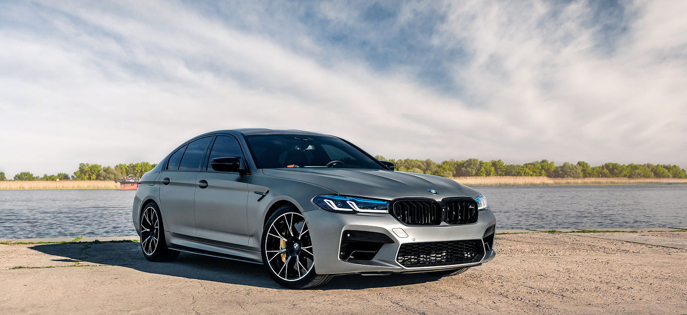 New BMW M5 F90 Competition on the background of the river.