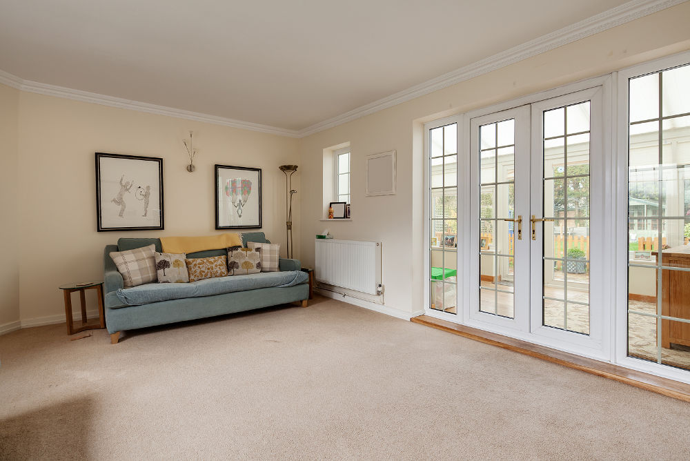 Sparcely furnished living room with white upvc windows and doors