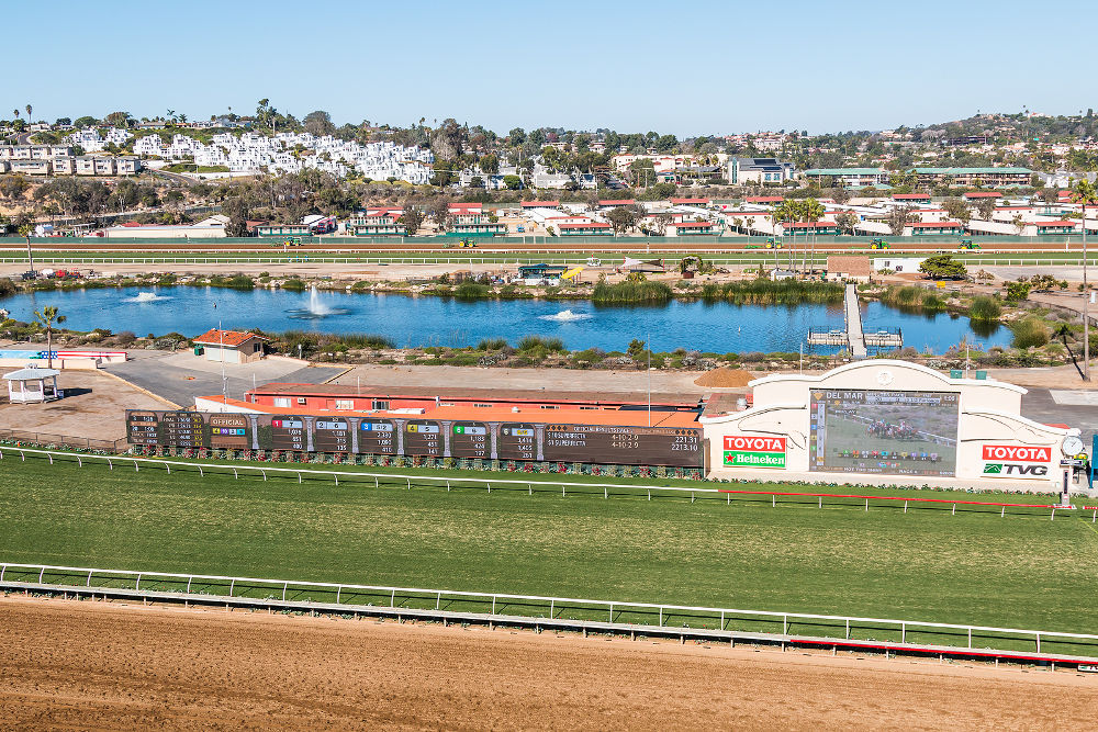 The grass and dirt racetracks along with the tote board and pond of the Del Mar horse racing track.