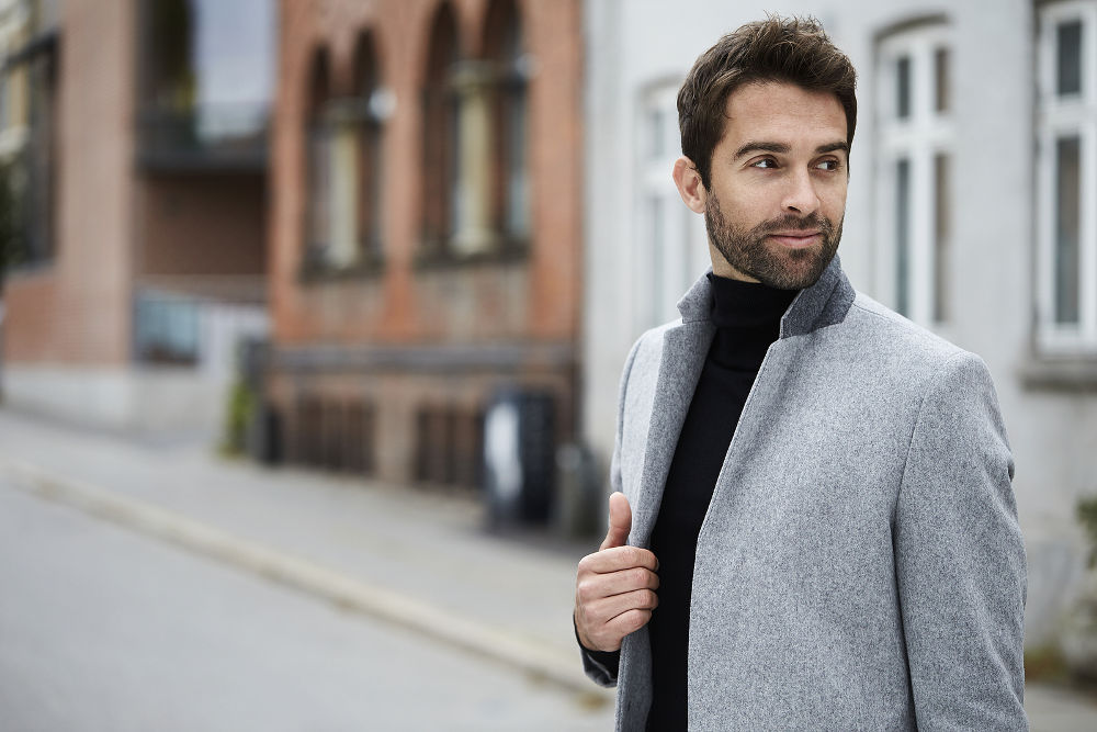 Smiling guy in grey overcoat looking away