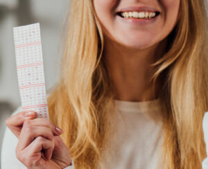 cropped view of woman showing winner gesture while holding lottery ticket