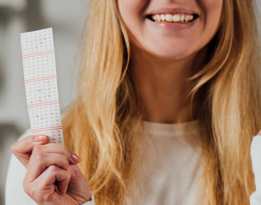 cropped view of woman showing winner gesture while holding lottery ticket