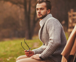 Fashionable portrait of a man sitting on a bench in the park