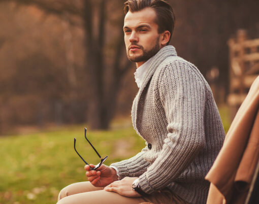 Fashionable portrait of a man sitting on a bench in the park