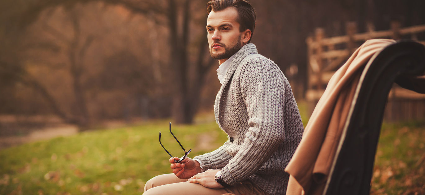 Fashionable portrait of a man sitting on a bench in the park