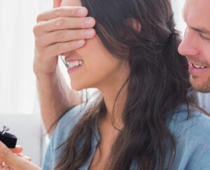 Man hiding his wifes eyes to offer her an engagement ring for a marriage proposal