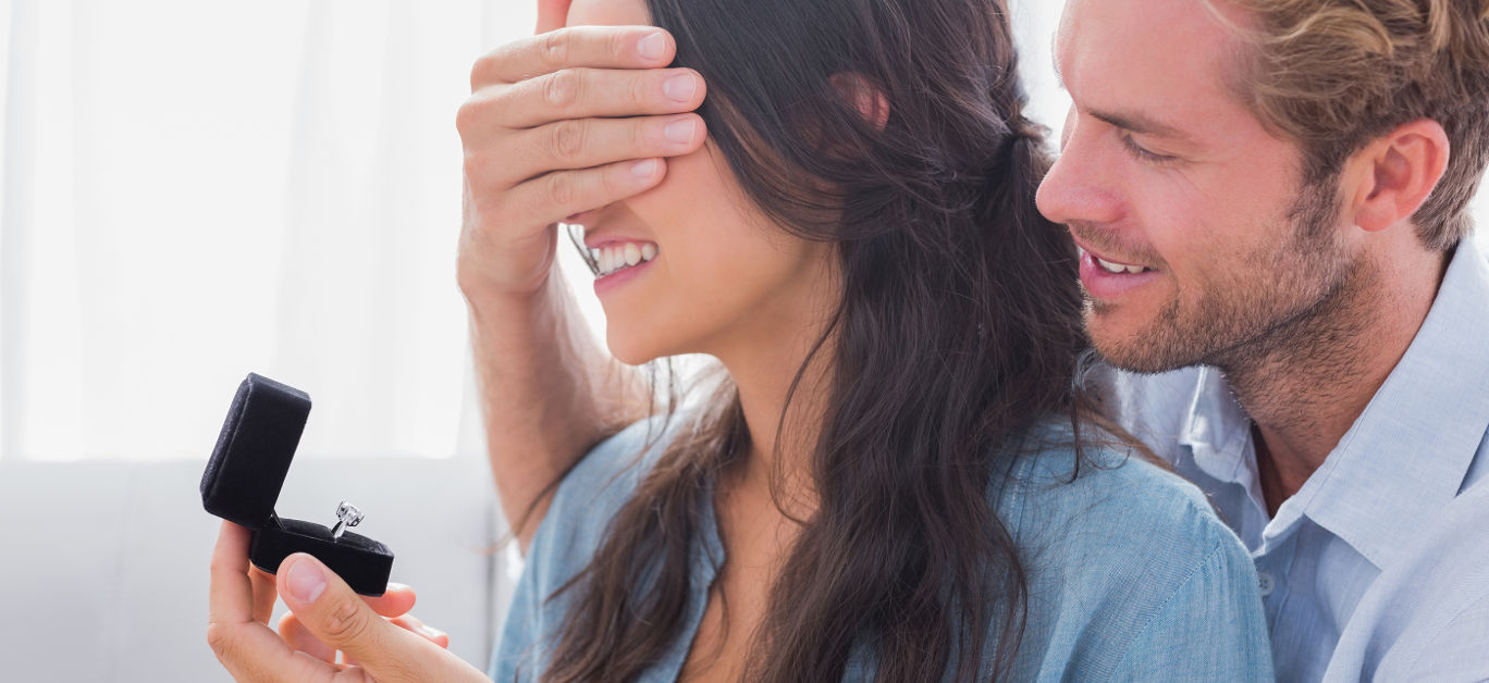 Man hiding his wifes eyes to offer her an engagement ring for a marriage proposal