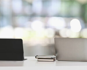 Office desk workspace with laptop, tablet and office supplies on white table in modern office with blurred background. Concept of orderly workplace.