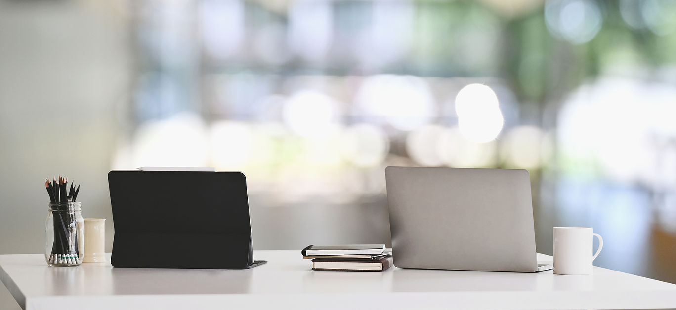 Office desk workspace with laptop, tablet and office supplies on white table in modern office with blurred background. Concept of orderly workplace.