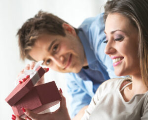 Young woman receiving a surprise gift box from her boyfriend at home.