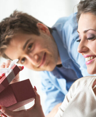 Young woman receiving a surprise gift box from her boyfriend at home.