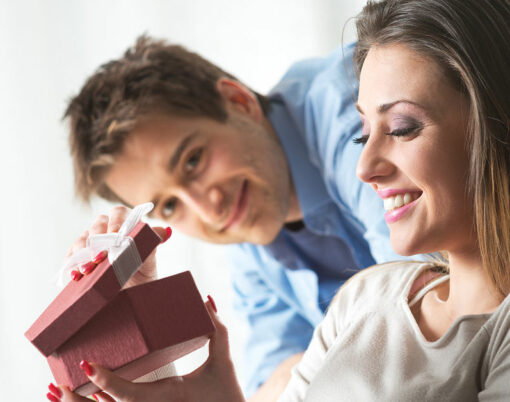 Young woman receiving a surprise gift box from her boyfriend at home.