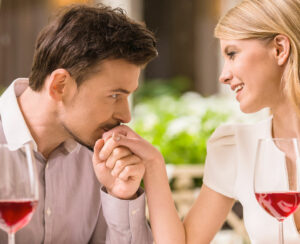 Young smiling couple enjoying the meal in gorgeous restaurant and drinking wine