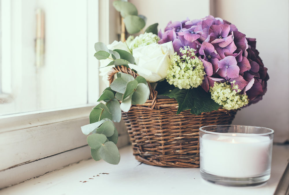 Big bouquet of fresh flowers, purple hydrangeas and white roses in a wicker basket on a windowsill, home decor, vintage style