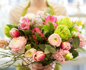 people, business, sale and floristry concept - close up of florist woman holding bunch at flower shop