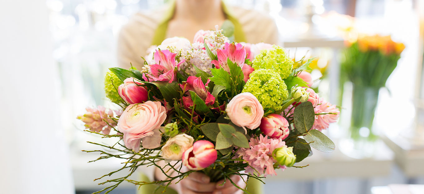 people, business, sale and floristry concept - close up of florist woman holding bunch at flower shop